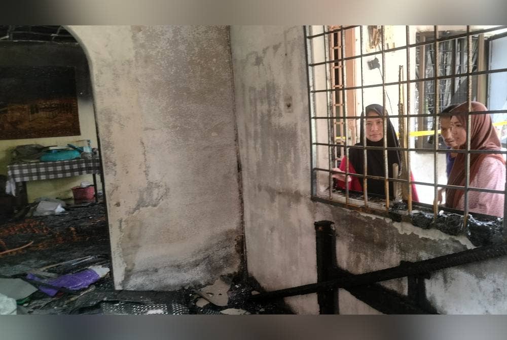 Nor Azuraida (kiri) dan adiknya Nurul Aina Fitrah meninjau keadaan dalam rumahnya yang hampir musnah dalam kejadian kebakaran pada Rabu.