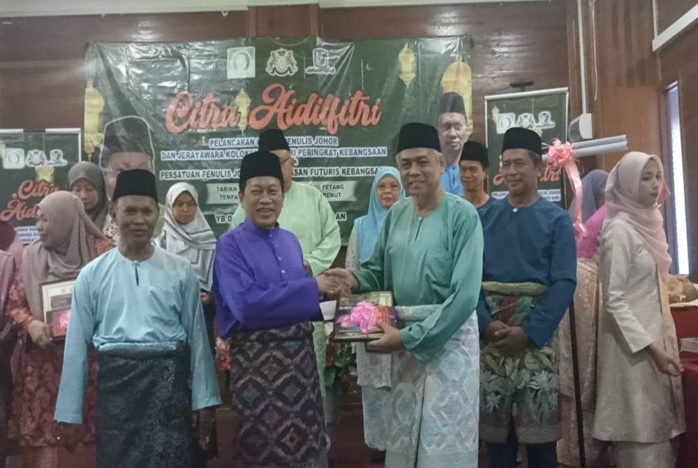 Ahmad (dua dari kiri) menyampaikan hadiah kepada pemenang Sayembara Penulisan Puisi sempena Sambutan Hari Raya anjuran Persatuan Penulis Johor di Rumah Citra Benut, pada Jumaat.