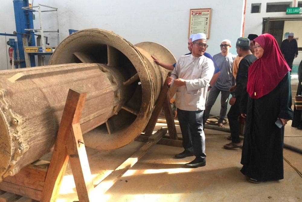 Mohd Faizul (kiri) melihat pam yang digunakan untuk membekalkan air kepada petani.