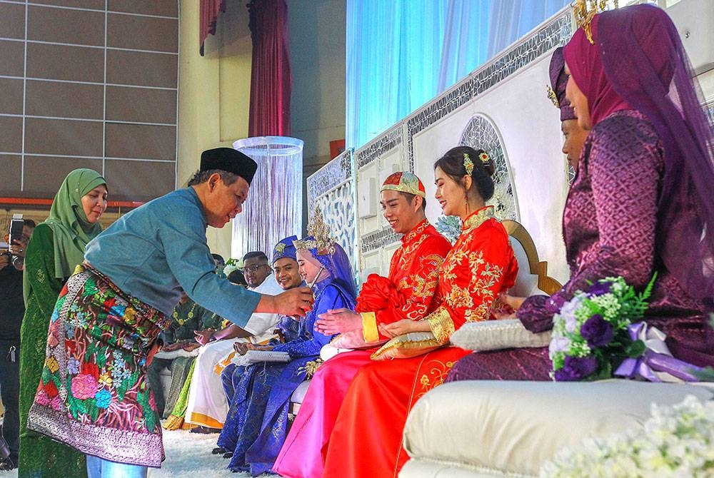 Aminuddin dan isteri merenjis air mawar kepada pengantin diraikan