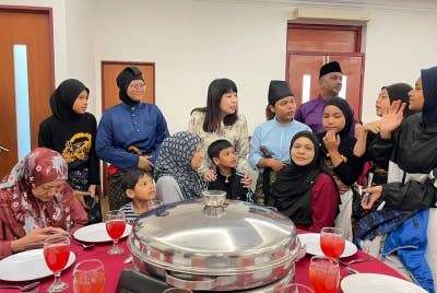 Hui Ying (berdiri, tiga dari kiri) beraamah mesra dengan tetamu yang hadir di Majlis Rumah Terbuka Hari Raya Aidilfitri Ahli Parlimen Tanjung pada Sabtu.