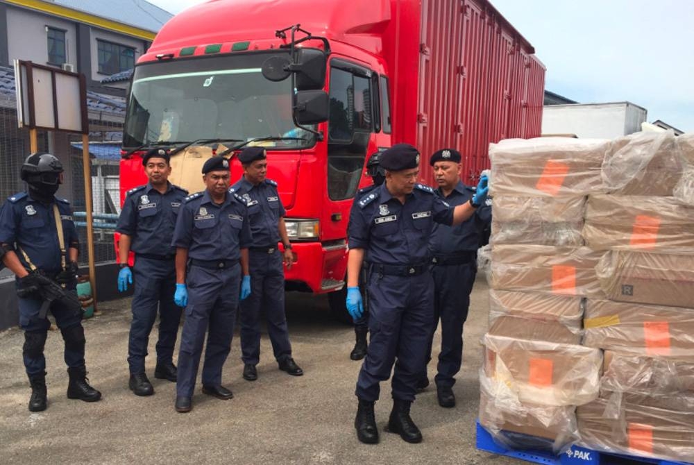 Wan Jamal Abdul Salam (kanan) melihat kotak-kotak mengandungi rokok seludup.