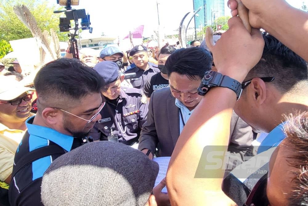 Hishamuddin (kiri) ketika menyerahkan memorandum kepada wakil Pejabat Ketua Menteri Sabah di hadapan Menara Kinabalu, Kota Kinabalu.