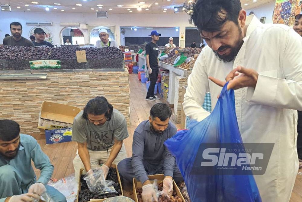 Majeed (kanan) membantu pekerjanya membungkus kurma.