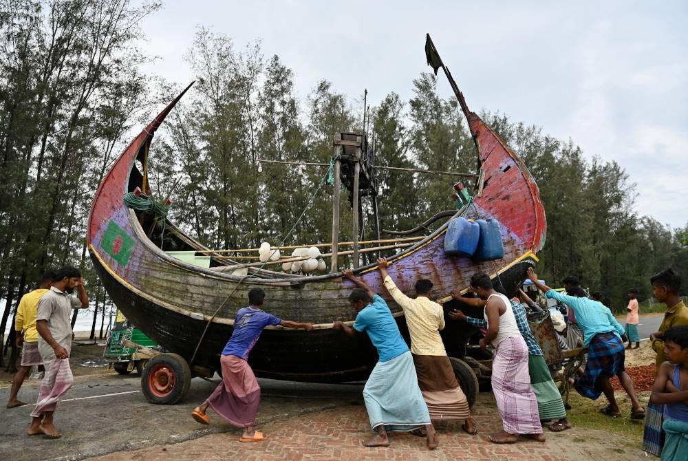 Nelayan memindahkan bot ke tempat selamat di Teknaf sebelum Siklon diramalkan melanda Bangladesh Ahad lalu. - AFP