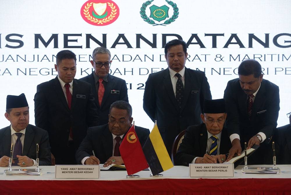 Muhmmad Sanusi (duduk dua kiri) dan Shukri (duduk dua kanan) menandatangani perjanjian sempadan darat dan maritim antara Kedah Perlis di Wisma Darul Aman pada Ahad.