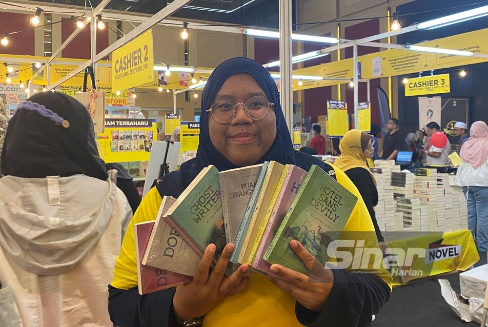 Anis Syamila menunjukkan Siri Gerbang Puaka yang laris dijual di reruai Grup Buku Karangkraf, PBAKL kali ke-40.