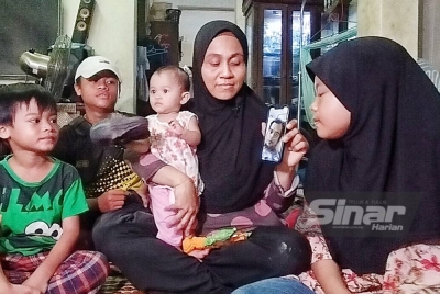 Siti Suryati (empat,kiri) bersama anak-anaknya melihat gambar arwah suaminya yang meninggal dunia pada 19 Mei lalu.