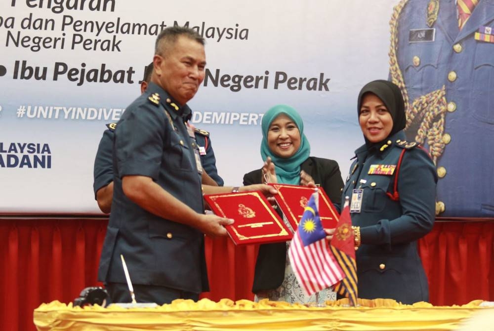 Azmi (kiri) menyerahkan nota serah terima tugas dan tongkat kuasa kepada Sayani yang akan mengambil alih jawatan Pengarah JBPM Perak pada Jumaat.