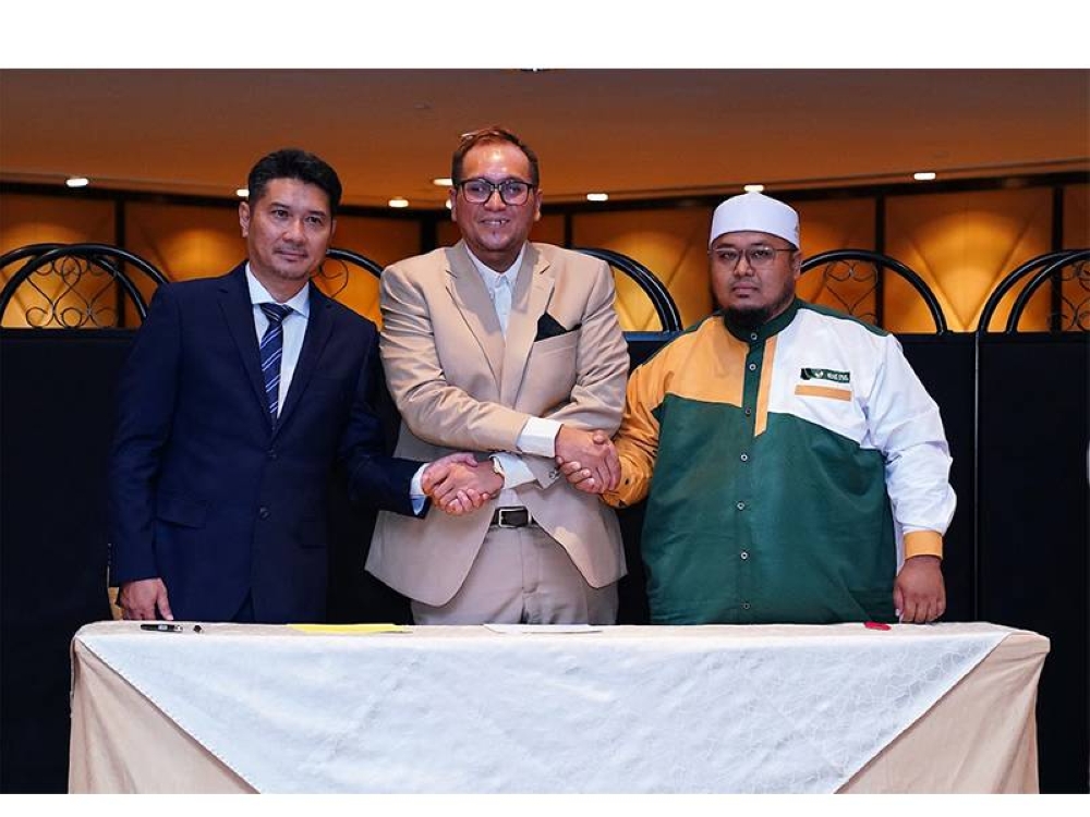 Muhammad Faisal (tengah) menyaksikan pemeteraian kerjasama bersama Alam Shah Travel & Tours Sdn Bhd.