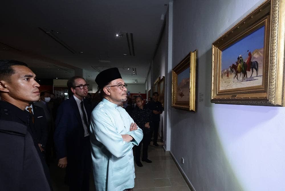 Anwar diberi penerangan oleh Pakar lukisan Oriantalis Claude Piening (kanan) ketika melawat pameran selepas Perasmian Pameran 'Orientalism Paintings' di Muzium Kesenian Islam Kuala Lumpur pada Jumaat. - Foto Bernama