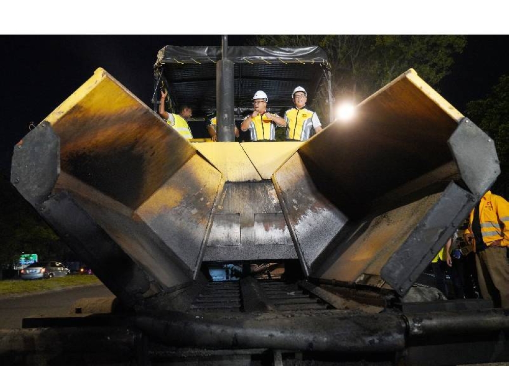 Amirudin (tengah) sambil diiringi Izham (kanan) melihat kerja-kerja turapan di Jalan 22/1, Persiaran Jubli Perak, Shah Alam pada Khamis malam.