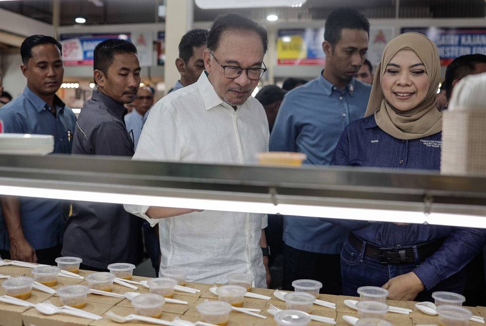 Anwar melihat pelbagai juadah makanan di medan selera pada majlis perasmian D'Anjung Selera Madani Jalan Jujur, Bandar Tun Razak pada Sabtu. - Foto Bernama