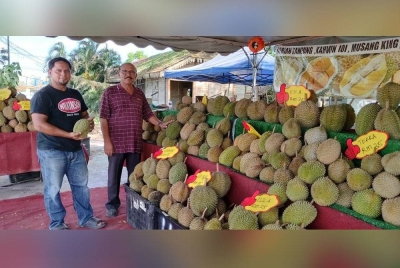 Mohd Hazrizal (kiri) ketika menunjukkan durian yang dijualnya bertentangan stesen keretapi Bahau.