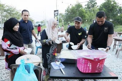 Mohd Kamarul (dua dari kanan) memasukkan pulut ke dalam mangkuk untuk diberikan kepada pelanggan di gerai durian di Jalan Gambang-Kuantan pada setiap hari Jumaat, Sabtu dan Ahad.