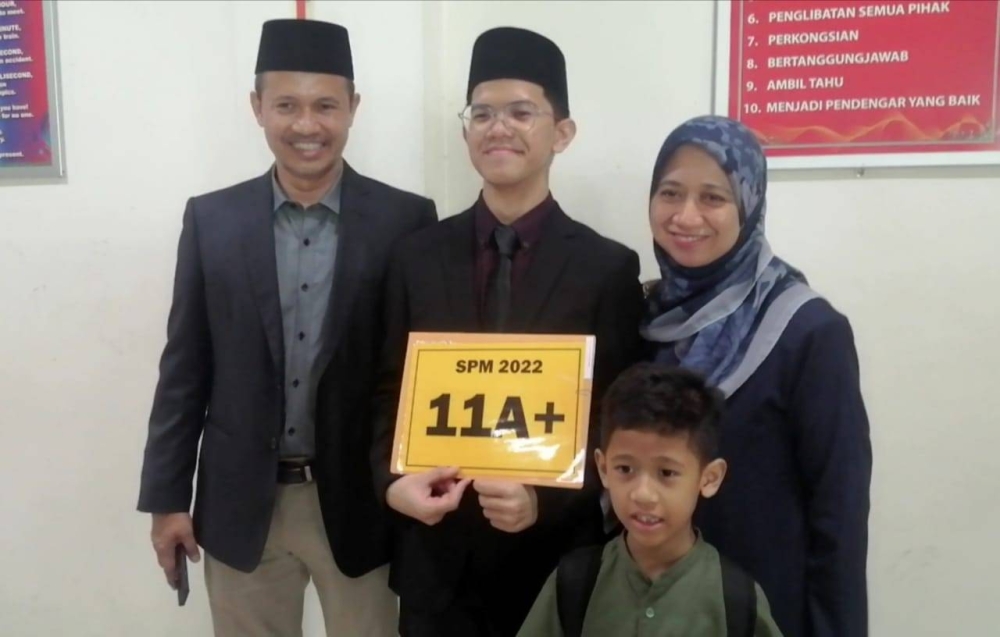 Danial (tengah) ditemani ibu bapa serta adik ketika mengambil keputusan SPM di SMA MAIWP pada Khamis.