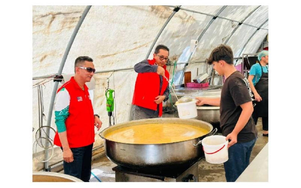 Mohd Yusni menyendukkan kuah dhal kepada salah seorang mangsa gempa bumi.