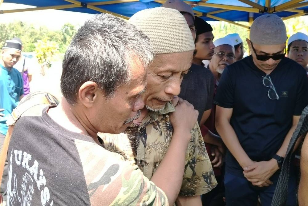 Abu Bakar ditenangkan saudara ketika jenazah tiga anak lelakinya dikebumikan.