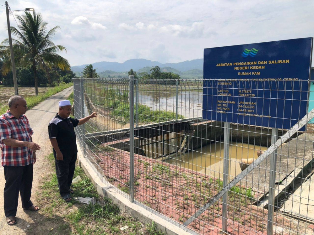 Othman (kiri) bersama petani meninjau Rumah Pam JPS di Kampung Tebing, Napoh pada Jumaat.