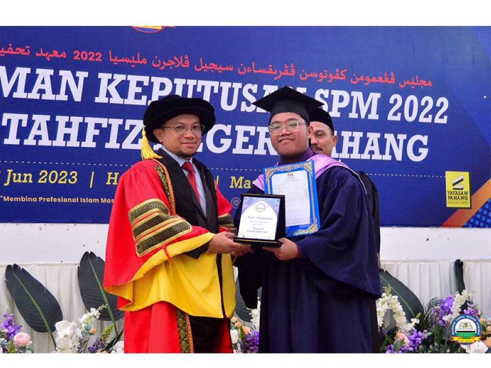 Nik Hadif Darwisy (kanan) menerima anugerah yang disampaikan oleh Ketua Pegawai Eksekutif MTNP, Mohd Lafzul Muda Al-Hafiz pada Majlis Pengumuman Keputusan SPM 2022 Maahad Tahfiz Negeri Pahang pada Khamis.