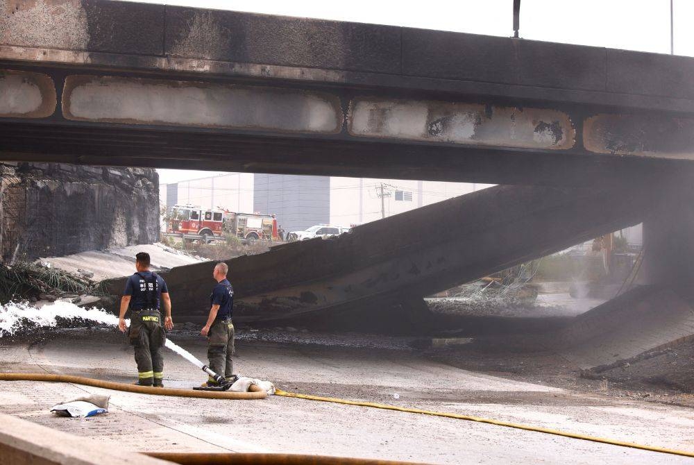 Anggota bomba meninjau lokasi kejadian selepas melakukan kerja-kerja memadam kebakaran. - Foto AFP