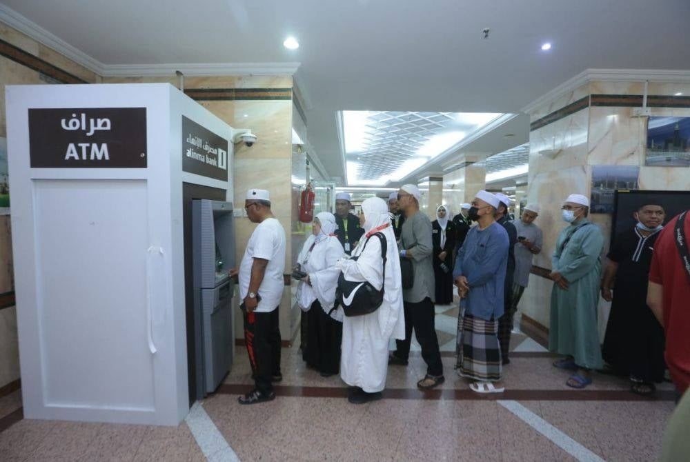 Jemaah haji beratur untuk mengeluarkan wang dari ATM.