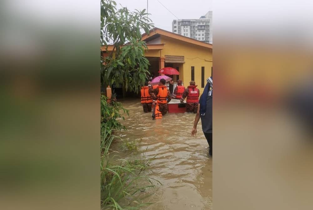 Anggota bomba menyelamatkan mangsa banjir kilat di sebuah rumah di kampung berkenaan. - Foto Bomba