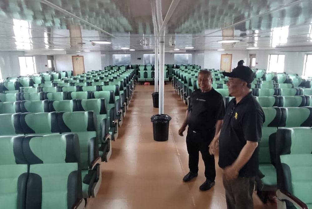 Ismail (kanan) menunjukkan keadaan tempat duduk My Roro Tiga yang boleh memuatkan sehingga 220 penumpang di Kuala Kedah pada Selasa.