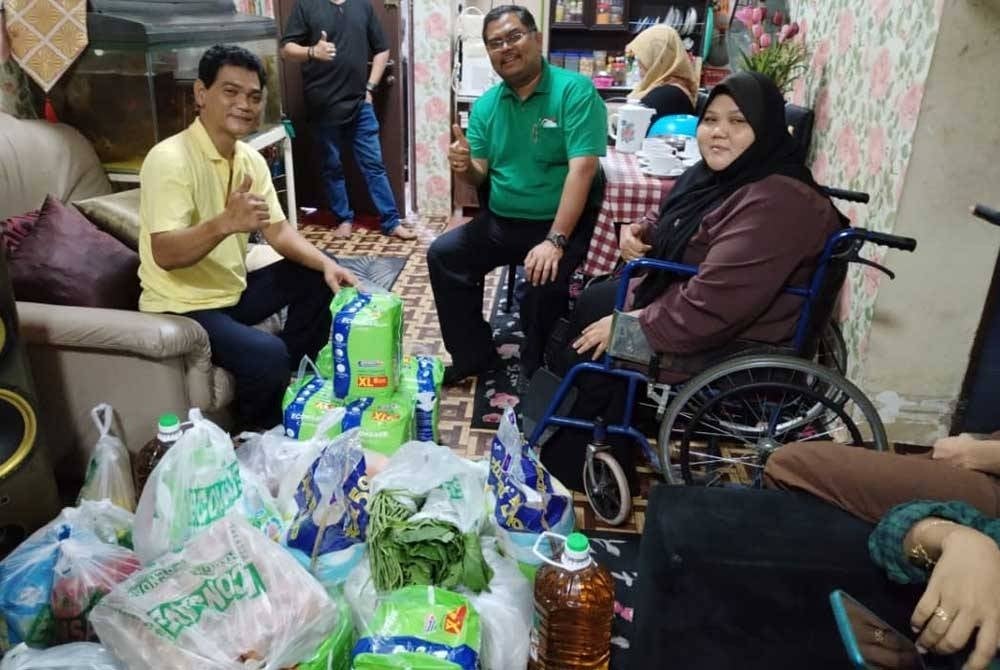 Dari kiri: Mas Imran (tengah) menyampaikan sumbangan barangan keperluan asas kepada Fadzil dan Fazlenyana.