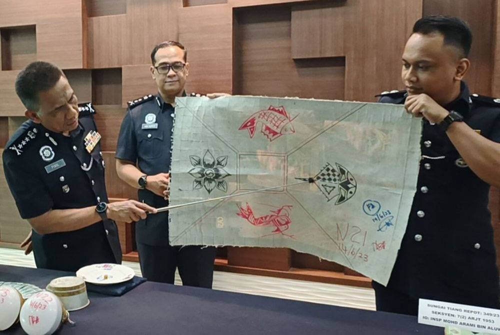 Fisol (kiri) menunjukkan antara kelengkapan judi belangkas yang dirampas dalam serbuan di ladang kelapa sawit, Kampung Titi Akar, Pendang, pada petang Rabu.