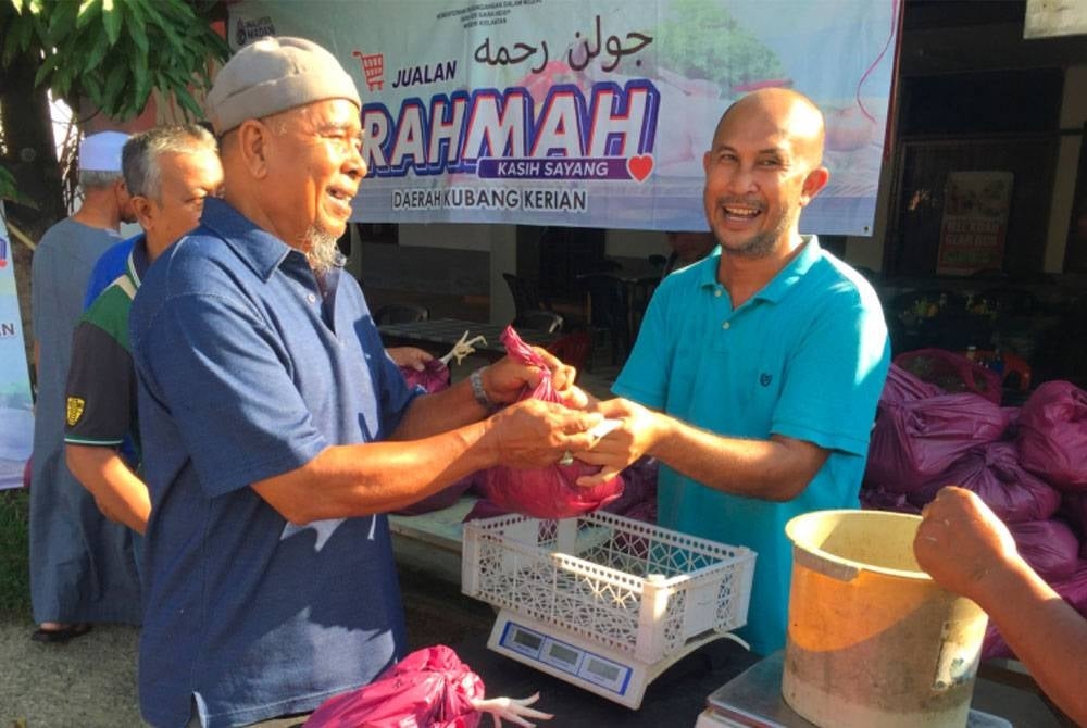 Abdullah (kiri) membeli dua ekor ayam di Program Jualan Rahmah di Kampung Parit Limbat, Kota Bharu.
