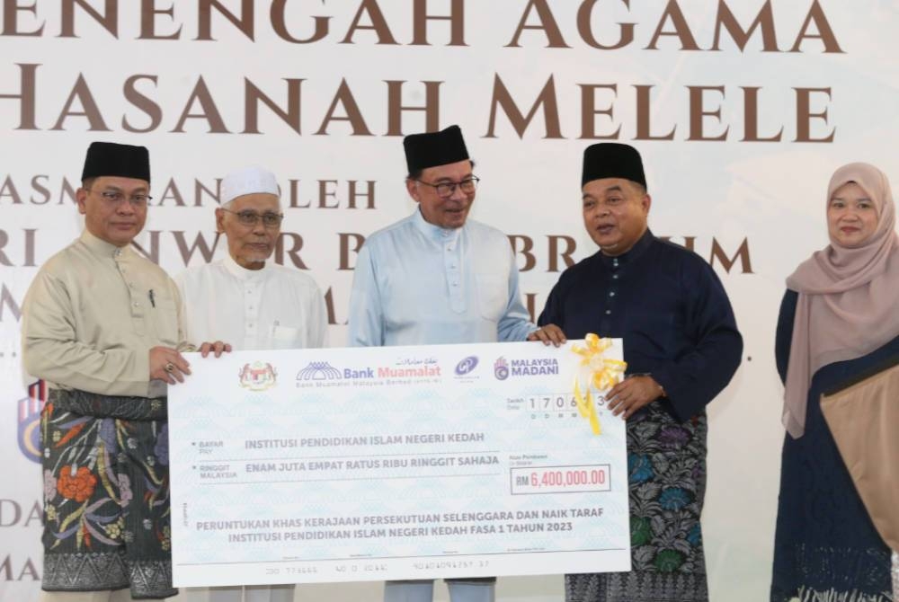 Anwar (tengah) menyampaikan cek sumbangan kepada institusi pendidikan Islam di Kedah sebagai simbolik penyerahan pada majlis sambutan Jubli Intan SMA Nahdhah Hasanah Melele, Kodiang pada Sabtu.