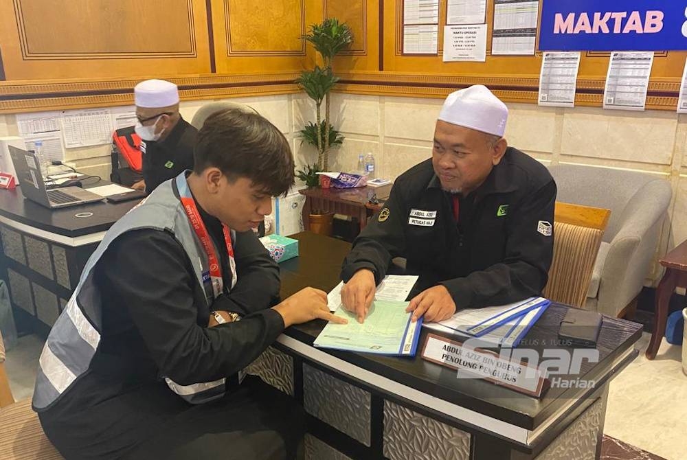 Muhammad Haqim (kiri) membantu petugas haji di pejabat maktab.