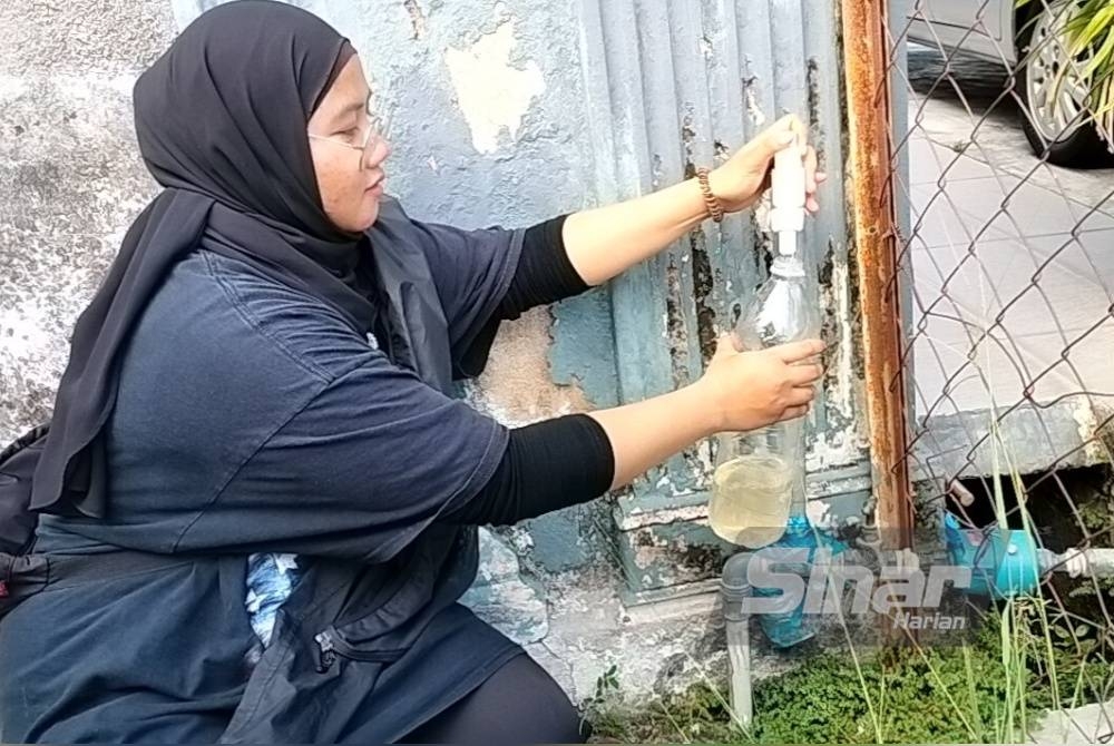 Intan Aleeya Farhana menadah air di rumahnya yang didakwa keruh.