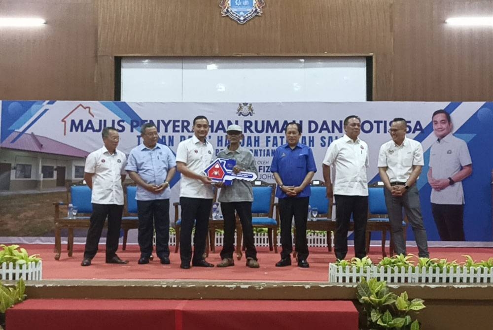 Onn Hafiz (tiga dari kiri) menyerahkan kunci rumah kepada penduduk yang akan berpindah ke penempatan baharu di Benut.