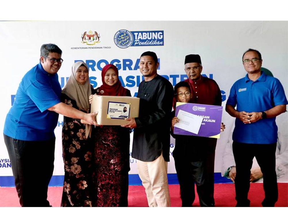 Norliza (tiga dari kiri) menyampaikan sumbangan kotak makanan dan replika kad Simpan SSPN Prime kepada salah seorang penerima sumbangan.