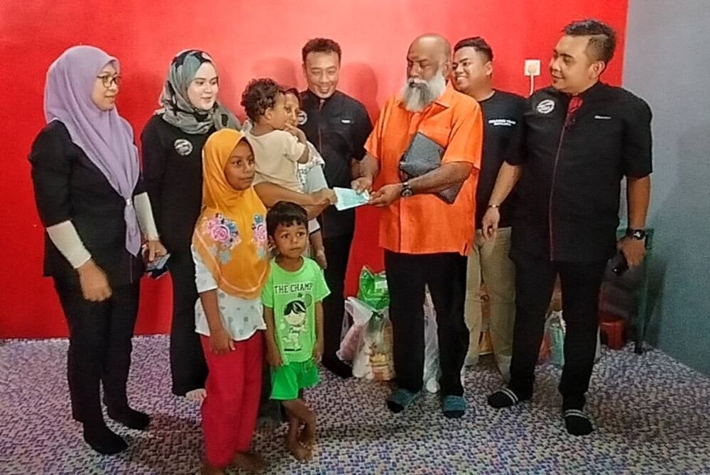 Maria (tiga,kiri) menerima sumbangan yang disampaikan Ganesan (lima dari kiri) dan Ashwad (enam dari kiri) di Rumah Pangsa Taman Merdeka di Melaka pada Selasa.