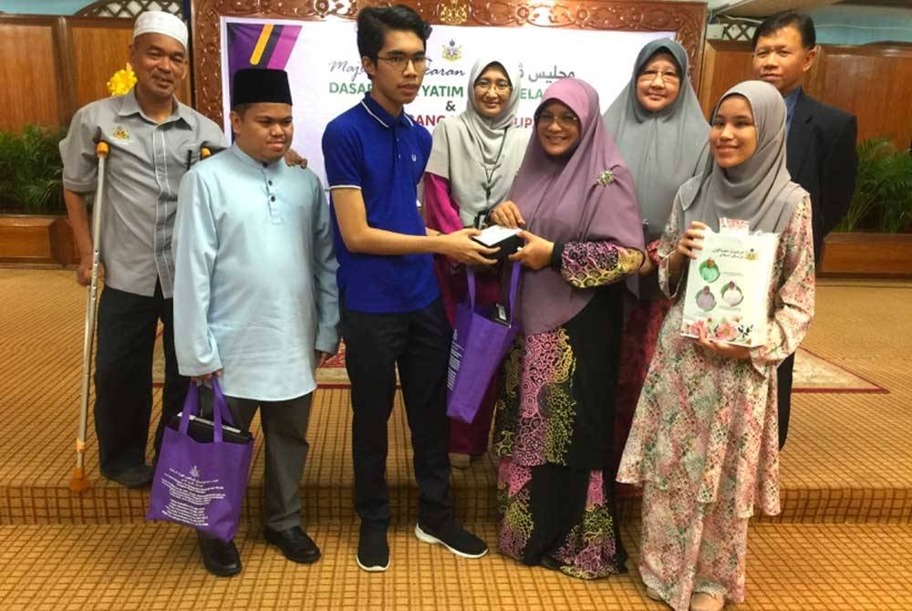 Mumtaz barisan depan (dua dari kanan) menyampaikan hadiah kepada anak yatim OKU yang cemerlang pada Sijil Pelajaran Malaysia 2022.