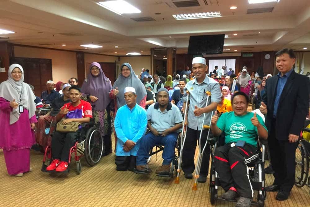 Mumtaz (tiga dari kiri) bergambar bersama kumpulan penerima kerusi roda elektrik di Kota Darulnaim, Kota Bharu pada Selasa.