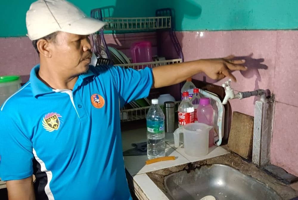 Awih menunjukkan paip air di rumahnya yang tidak mengalirkan setitik air pun.