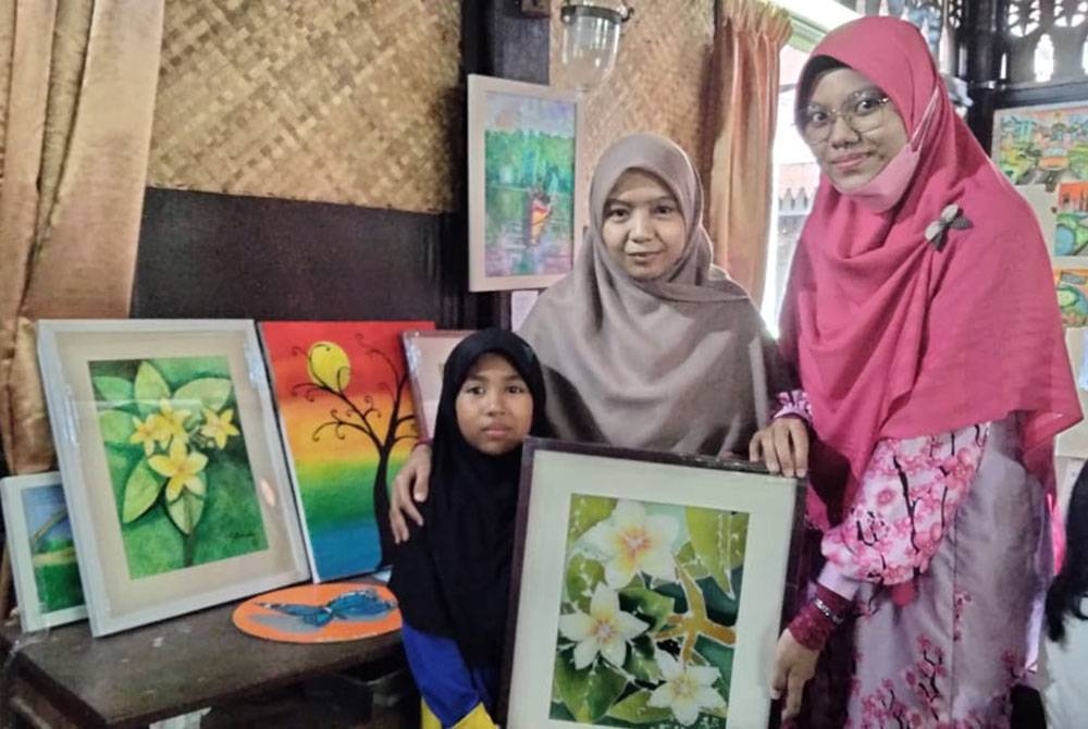Fatimah Aisyah (kiri) bersama lukisan yang dihasilkan di Kampung Kraftangan.
