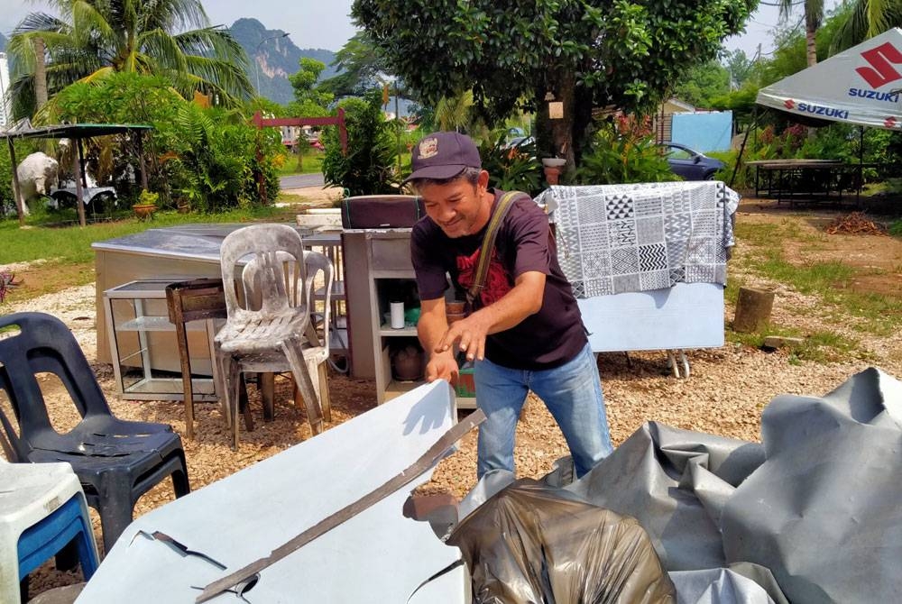 Nashrun mengumpul peralatan gerainya yang rosak akibat ribut di Taman Perpaduan di sini pada Jumaat.