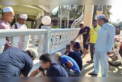Arama (kanan) dan Nagamani melihat OBB mengecat pagar Masjid Kemumin pada Program CSR Penghuni Parol Bersama Ahli Jawatankuasa Masjid Kemumin, Pengkalan Chepa pada Jumaat.