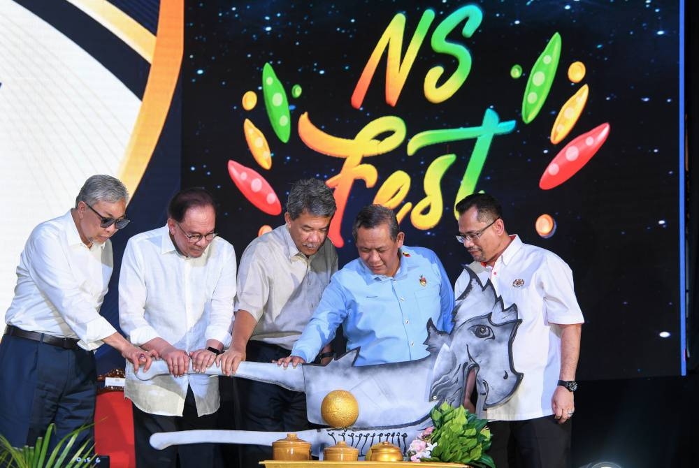 Anwar (dua dari kiri) bersama Ahmad Zahid (kiri) menyempurnakan gimik pelancaran Sentuhan Kasih Desa di Dataran Nilai, hari ini. Foto Bernama