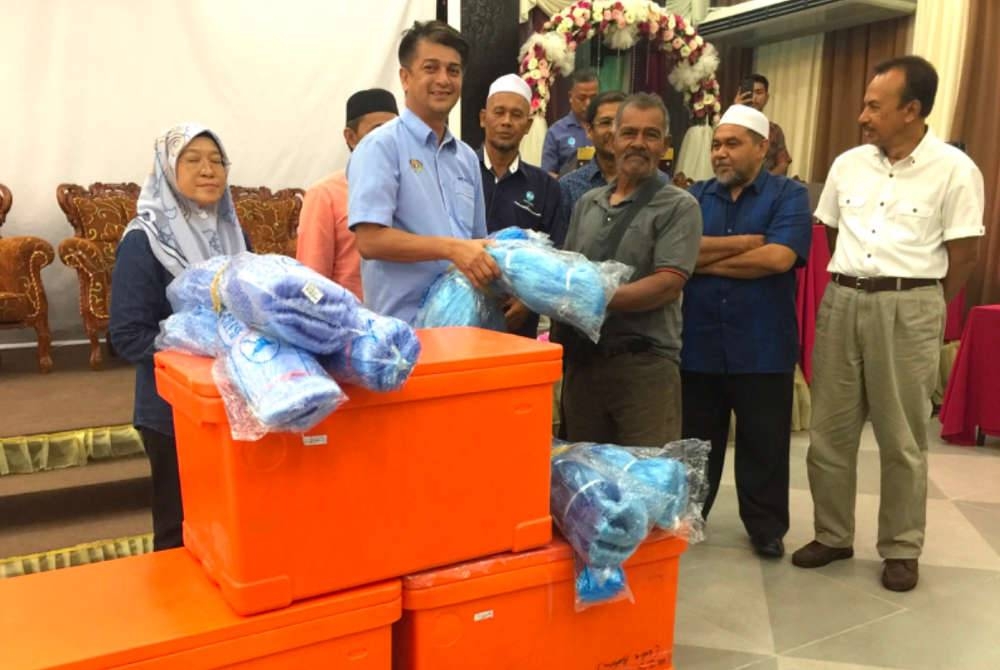 Penerima, Ab Salam Yacub (tiga dari kanan) menerima sumbangan peralatan menangkap ikan yang disampaikan oleh Muhammad Faiz (dua dari kiri) di Kelantan pada Ahad.