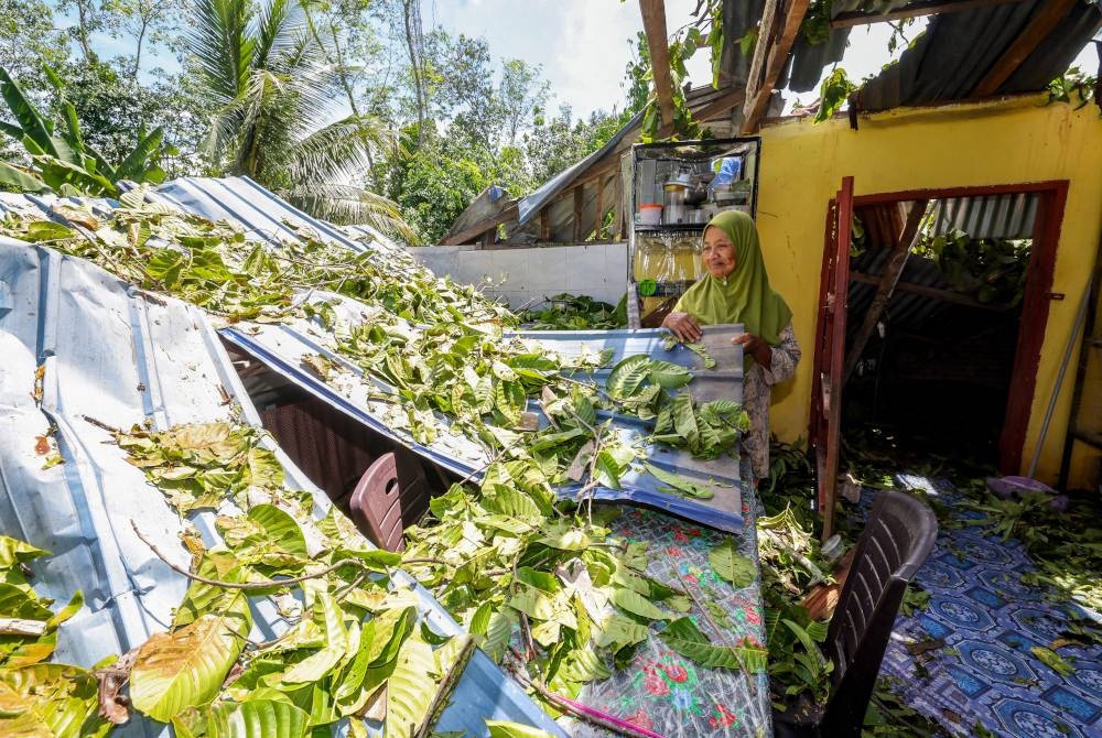 Mangsa kejadian ribut Fatimah Salleh, 62, membersihkan ruang dapur rumahnya, yang dilanda ribut petang Ahad. - Foto Bernama