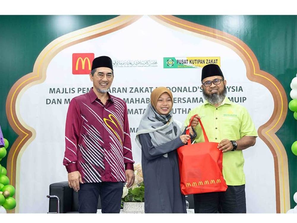 Salah seorang anak yatim menerima sumbangan keperluan sukan daripada Dr Asmadi (kanan).