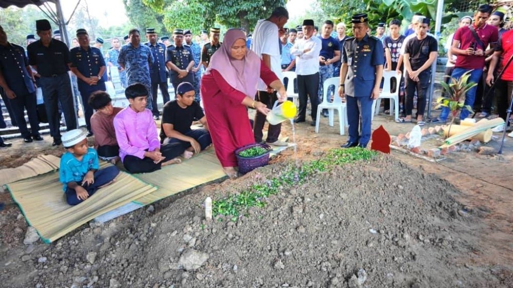 Ibu kepada Allahyarham Mohd Iqmal, Rozana Mustapa, 51, menyiram pusara anaknya yang selamatkan dikebumikan di Tanah Perkuburan Islam Kampung Rawa Ulu pada Isnin.