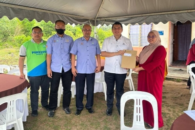 Hisyam (tengah) bersama Mohamad Nizar menyerahkan baucar bayaran faedah-faedah Perkeso kepada wakil keluarga pencarum di Kampung Tanah Putih, Pekan pada Ahad.