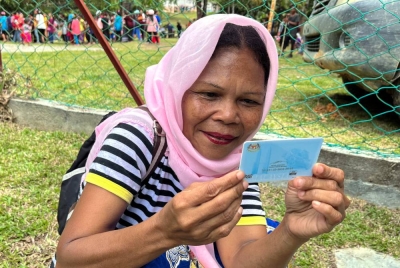 Penduduk Orang Asli suku kaum Temiar, Ajah Adik, 48, melihat kad pengenalan yang baharu sahaja diterima daripada wakil Jabatan Pendaftaran Negara (JPN) sempena Program Outreach dan Kembara Mesra Rakyat di Pos Belatim, pada Isnin. - Foto Bernama